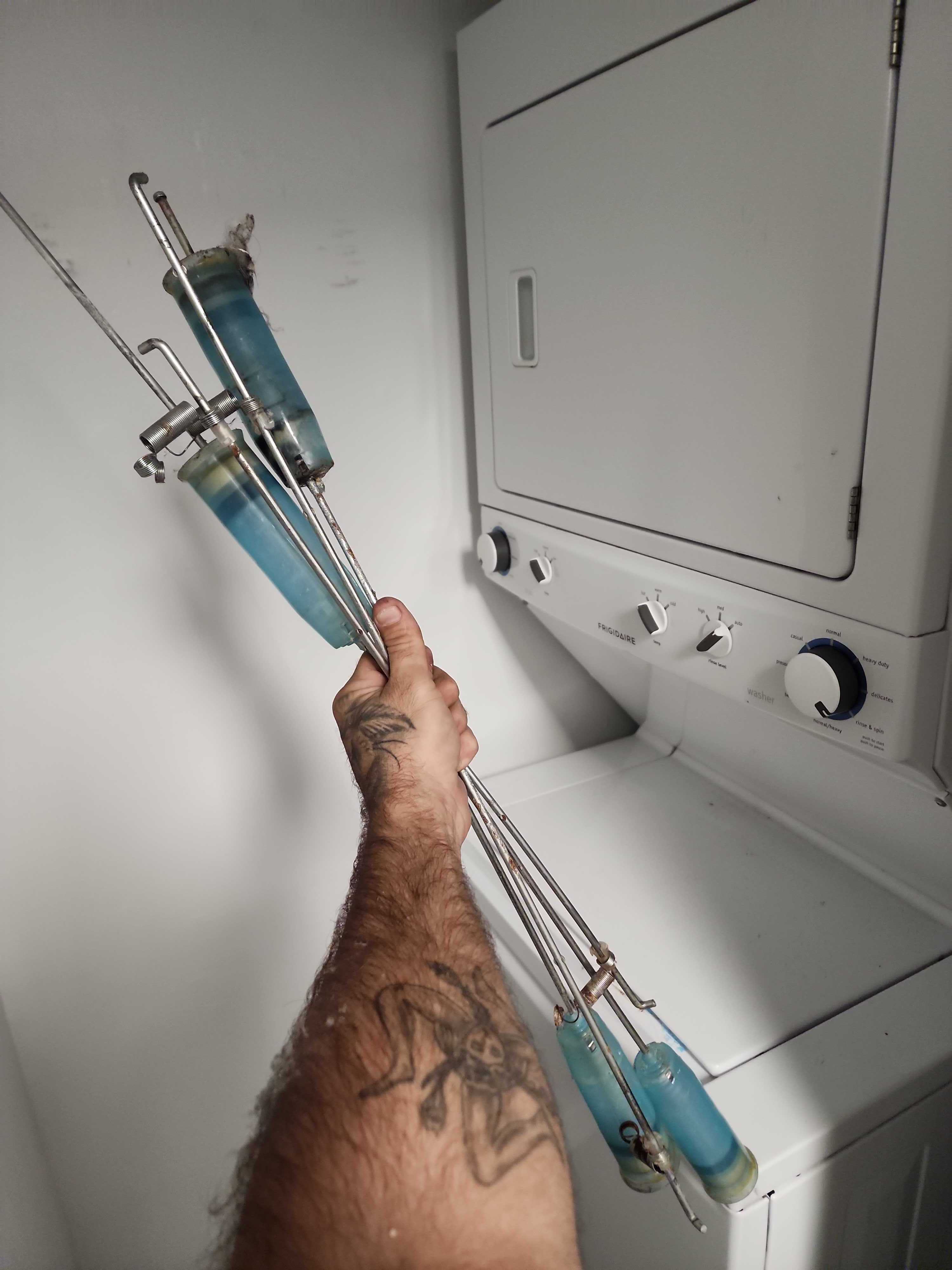 Technician holding replaced washer suspension rods for Electrolux FFLE3911QW0 laundry center in Lauderhill FL RR0098