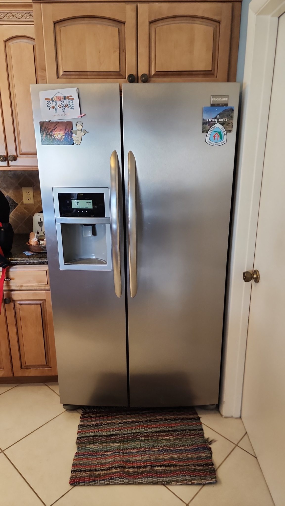 Stainless steel Frigidaire Side-by-Side Refrigerator experiencing water dispenser flow issues in a residential kitchen.