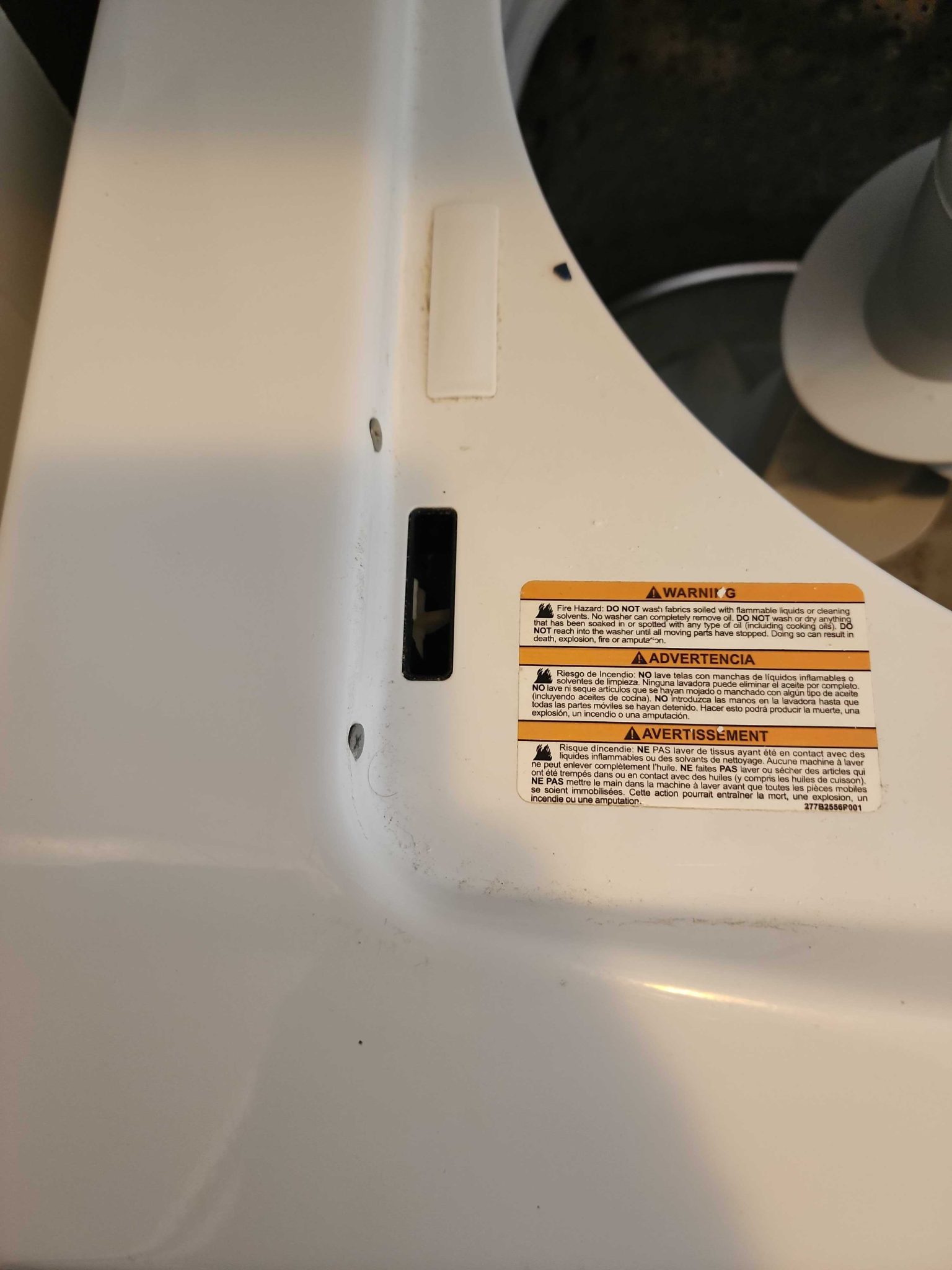 Close-up interior view of the washer lid lock slot and warning labels on a GE laundry center where the locking assembly failed.