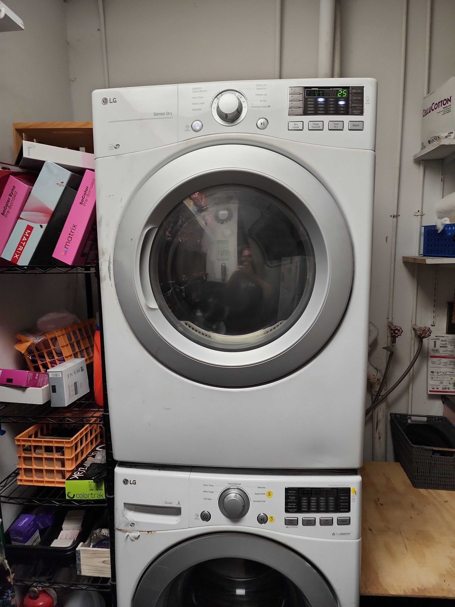 Front view of a fully assembled and refurbished white LG stacked electric dryer in a salon, operating smoothly and reliably after having its belt, drum rollers, and idler pulley replaced.